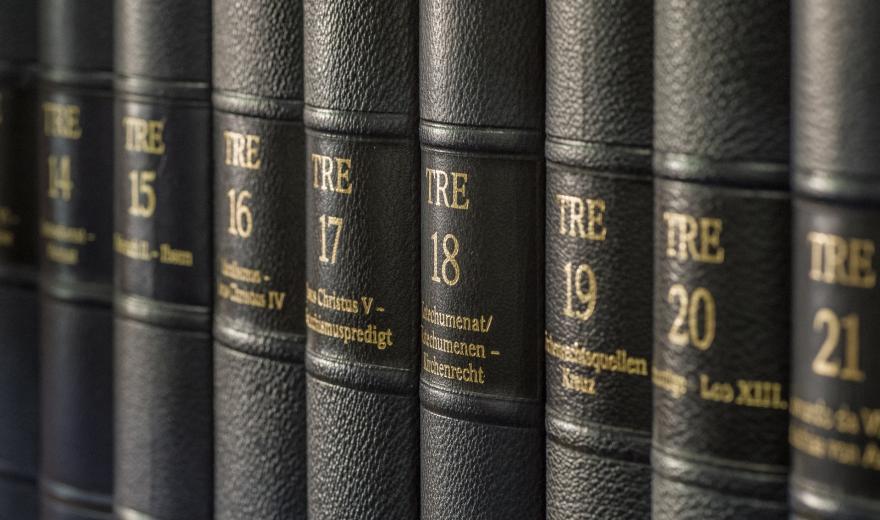Diagonaal over het beeld lopende afbeelding van bruin lederen bandruggen van een encyclopedie, van links naar rechts aangeduid en genummerd van TRE 14 tot TRE 21.